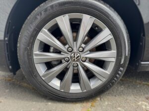Silberne Volkswagen-Autofelge mit Goodyear-Reifen und 10 Speichen, auf grauem Hintergrund.