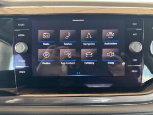 Touchscreen mit verschiedenen Auto-Funktionen, Symbole in Blau, darunter Navigation und Radio.