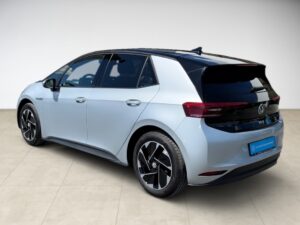 Silberner PKW, modernes Design, schwarze Fenster, markante Scheinwerfer und Dachspoiler.