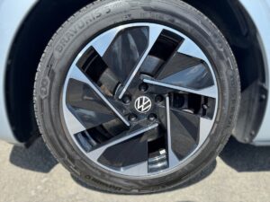 Nahaufnahme eines modernen Autoreifens mit stylischer, schwarz-silberner Felge und VW-Logo.