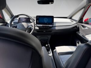 Innenraum eines modernen Autos mit grauen Sitzen, großem Bildschirm und multifunktionalem Lenkrad.