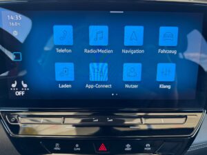 Ein digitales Display im Auto zeigt Apps und Symbole auf blauem Hintergrund an.