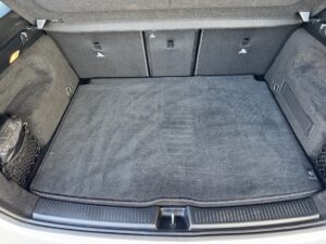 Kofferraum eines Autos mit grauem Teppich und Seitentaschen aus Netzmaterial.