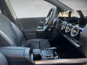 Innenraum eines modernen Autos mit schwarzem Leder, roter Naht und glänzenden Armaturen.