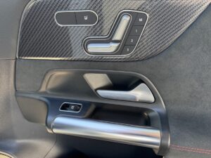 Autotür mit Metallgriffen, Sitzverstellungstasten und Kohlefaser-Textur.