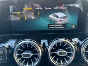 Auto-Display mit Funktionen, zentraler Lüftung und blauem Bildschirm, zwei silberne Lüftungen.