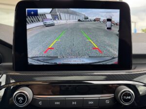 Auto-Rückfahrkamera-Ansicht auf Bildschirm mit Warnhinweis und Parkplatzdarstellung.