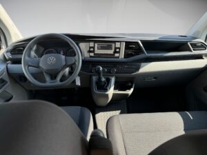 Innenansicht eines Autos, graue Sitze, schwarzes Armaturenbrett, modernes Design, Schalthebel sichtbar.