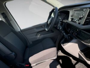 Innenraum eines Fahrzeugs mit schwarzem Armaturenbrett und Lenkrad, graue Sitze.