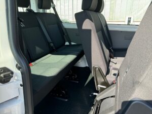 Innenansicht eines Fahrzeugs mit schwarzen Sitzen und Haltegriffen; Sonnenlicht fällt herein.