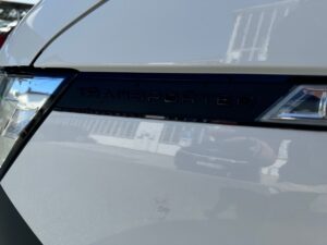 Nahaufnahme eines weißen Autos mit dem Schriftzug "Transporter" in schwarzer Farbe.