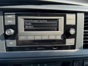 Autoradio-Display auf Deutsch, zeigt "Einstellungen System", Optionen: Radio, Medien.