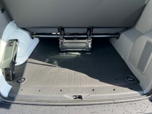 Der Kofferraum eines Autos mit umgeklappter Rückbank, schwarzer Boden, silberne Metallteile.