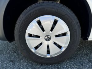 Nahaufnahme eines silbernen Volkswagen-Rads mit Bridgestone-Reifen auf Kieselsteinen.