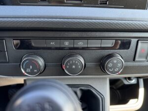 Armaturenbrett eines Autos mit Klimasteuerung und mehreren Knöpfen und Drehreglern.