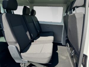 Innenraum eines Wagens mit grauen Stoffbezügen und drei Sitzreihen, leeres Fahrzeug.