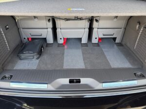 Offener Kofferraum eines Autos mit grauem Teppich und drei umgeklappten Rücksitzen.
