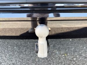 Nahaufnahme einer Anhängerkupplung an einem Auto, mit glänzendem schwarzen Lack und reflektierenden Details.