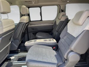 Innenraum eines Vans mit grauen und beigen Sitzen und großen Fenstern.