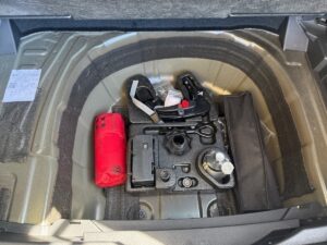Das Reserveradfach eines Autos mit Werkzeug und rotem Erste-Hilfe-Set.