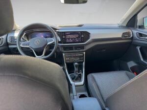 Innenansicht eines Autos mit grauer Polsterung, schwarzem Armaturenbrett und Lenkrad.