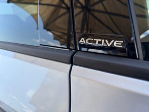 Nahaufnahme eines silbernen Autos mit einem "ACTIVE"-Logo auf schwarzem Rahmen.