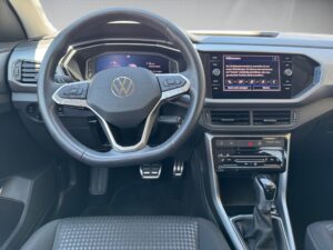 Lenkrad und Armaturenbrett eines Volkswagen-Autos mit digitalem Display und schwarz-grauer Konsole.