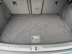 Kofferraum eines Autos mit grauem Teppichbelag und rechteckigem Fach in der Mitte.