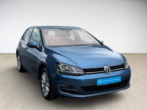 Blauer VW Golf vor hellem Hintergrund, Seitenansicht, schlichtes Design, kein erkennbarer Ausdruck.