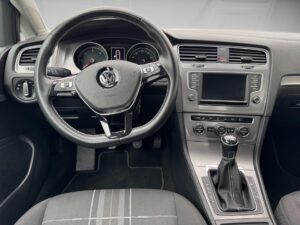 Lenkrad und Armaturenbrett eines Volkswagen mit schwarzer Innenausstattung und Grautönen.