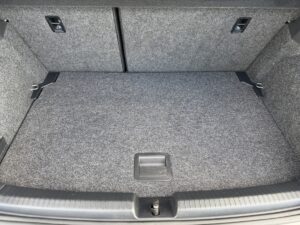 Grauer Kofferraum eines Autos in ordentlichem Zustand mit strukturierter Teppichoberfläche.