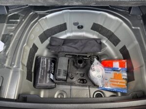 Autokofferraum mit Ersatzreifenfach, Verbandskasten, Werkzeugtasche und Notfallsets, grau.