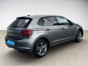 Silbergrauer VW Polo von hinten rechts, in einem hellen Raum auf beigem Boden geparkt.
