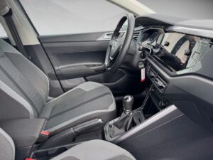 Innenraum eines modernen Autos mit schwarzem Polster, manuellem Getriebe und multifunktionalem Lenkrad.