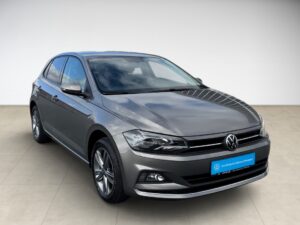 Silberner VW Polo mit glänzenden Felgen, vorne rechts ausgerichtet, auf hellem Boden.