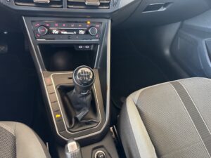 Autoinnenraum mit schwarzem Schaltknüppel und grauen Sitzen, modern gestaltet.