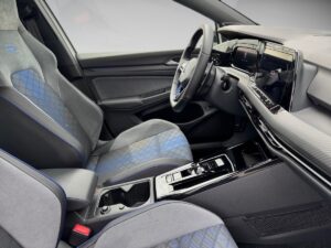 Grauer Auto-Innenraum mit modernen Sitzen und blauer Akzentnaht, Lenkrad und Display sichtbar.