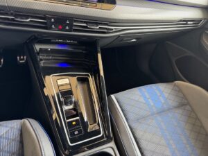Innenraum eines Autos mit modernem Schalthebel und blau-grauen Sitzen, ohne Personen.