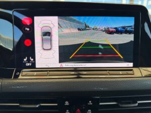Rückfahrkamera-Display im Auto, zeigt Parkplatz mit bunten Linien zur Unterstützung des Einparkens.