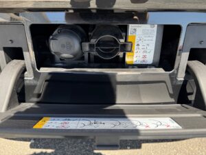 Nahaufnahme einer Autosteckdose, umgeben von Anweisungen und Symbolen, in schwarzem Rahmen.