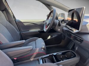 Innenraum eines modernen Autos mit grau-schwarzen Sitzen und roten Akzenten, große Displays vorn.