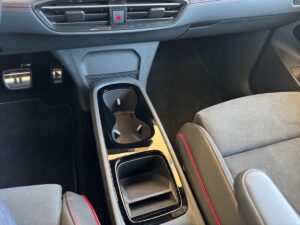 Autokonsole mit Getränkehaltern, schwarz, silberne Pedale, rote Ziernähte, modernes Design.