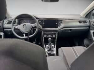 Innenraum eines Autos mit schwarzem Armaturenbrett, Schalthebel und Lenkrad mit Logo.