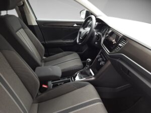 Innenraum eines Autos mit grauen Sitzen, modernem Armaturenbrett und Schaltknüppel in der Mitte.