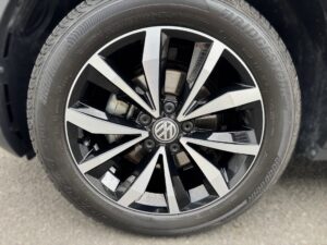 Nahaufnahme eines VW-Rads mit glänzenden schwarzen und silbernen Speichen auf Asphalt.