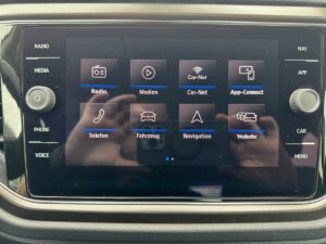 In der Mitte des Bildschirms befindet sich ein Interface mit App-Symbolen für Radio, Telefon und Navigation.
