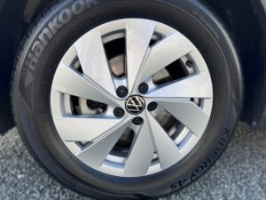 Nahaufnahme eines silbernen VW-Rads mit schwarzem Hankook-Reifen, steinerner Hintergrund.