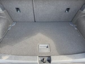 Leerer Kofferraum eines Fahrzeugs mit grauem Teppichboden und zwei Rücksitzriegeln.