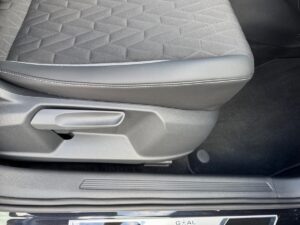 Ein Autositz in grauem Stoff mit geometrischem Muster und schwarzer Kunststoffverkleidung.
