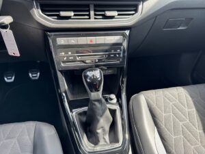 Nahaufnahme eines schwarzen Auto-Innenraums mit Schalthebel, Steuerung und Sitzdetails.